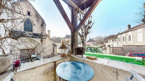 A rustic outdoor seating area with a metal table and chairs, a stone wall, and a vintage car parked nearby. - 2 bedroom nice home in Volnay (Volnay)