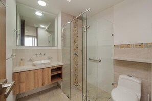Enjoy a refreshing shower in the glass-enclosed shower with a clear glass door, a sink, and a large mirror.