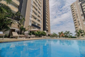 Relax by the pool surrounded by palm trees and lounge chairs.