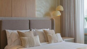 A modern bedroom with a large bed, a wooden accent wall, and a hanging light fixture. - Premium suite 25th floor (Cartagena de Indias)