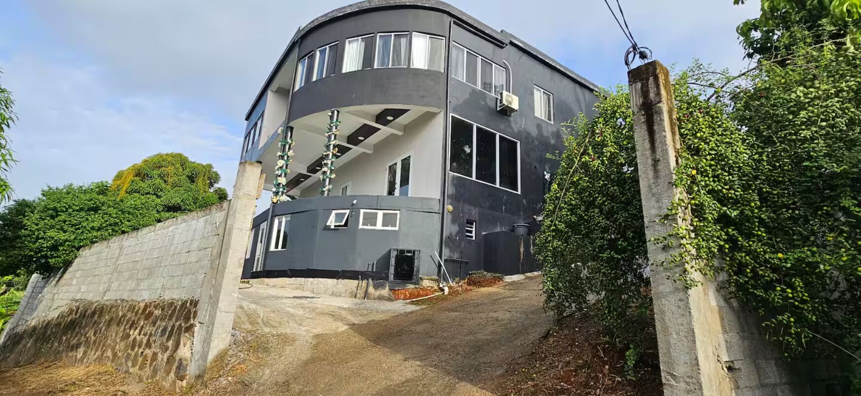 Um edifício moderno de dois andares com fachada curva, janelas amplas e uma varanda.