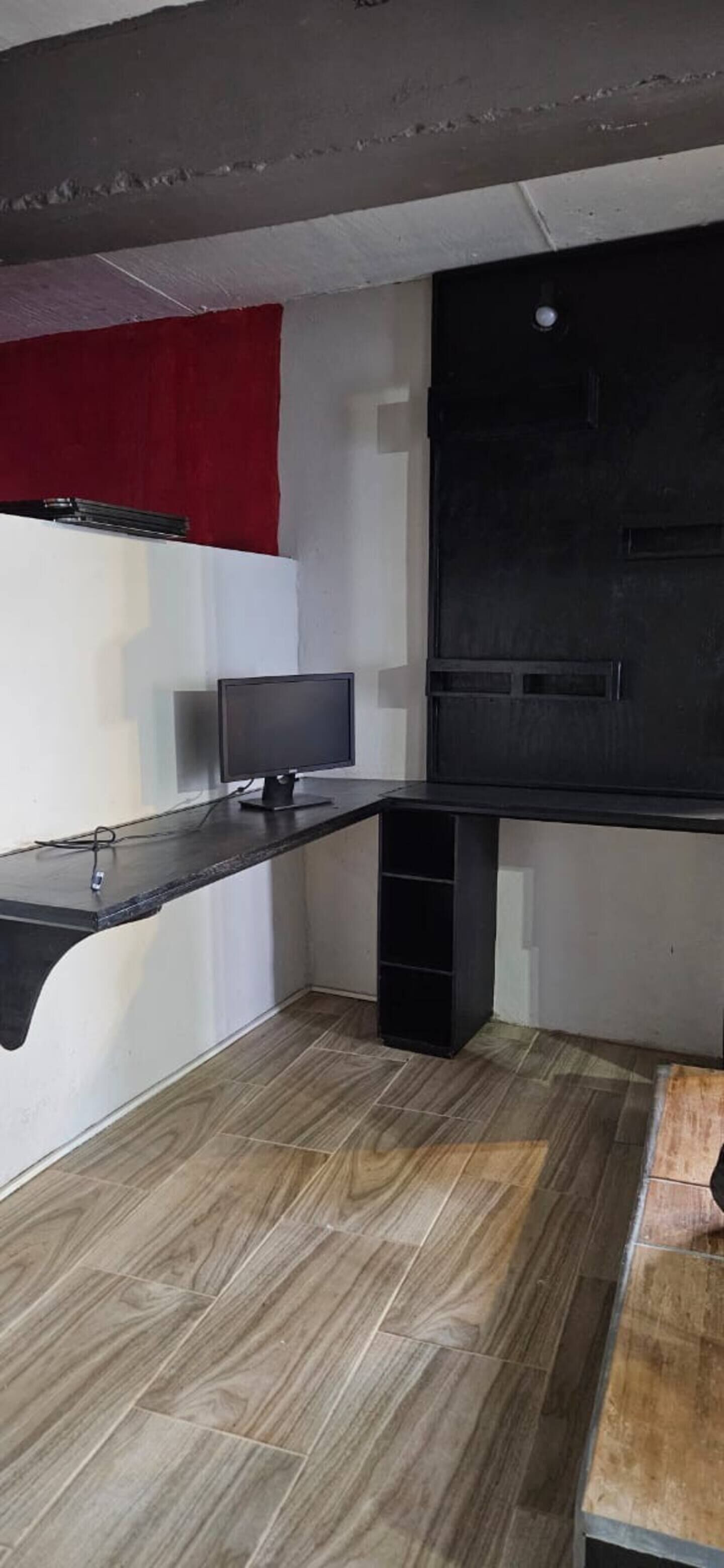 A corner room with a desk, a monitor, and a black cabinet.