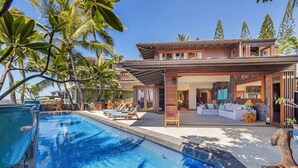 Une maison moderne dotée d’une piscine, d’un espace salon extérieur et de plantes tropicales.