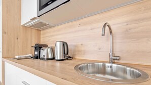 A modern kitchen with a stainless steel sink, a kettle, a coffee maker, and a microwave. - Pleasant apt with balcony -6P-Proche Disney/Paris (Champigny-sur-Marne)