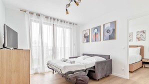 A modern bedroom with a bed, a TV, and artwork on the wall. - Pleasant apt with balcony -6P-Proche Disney/Paris (Champigny-sur-Marne)