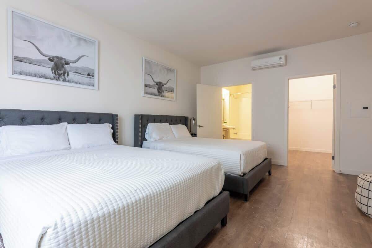 Une chambre d’hôtel avec deux lits, une grande fenêtre et une porte donnant sur une salle de bain.