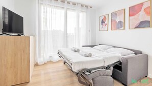 A modern bedroom with a bed, a TV, and artwork on the wall.