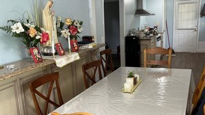A dining area with a long table covered in a white tablecloth, surrounded by wooden chairs. - The Holy Family of Nazareth (Cullman)