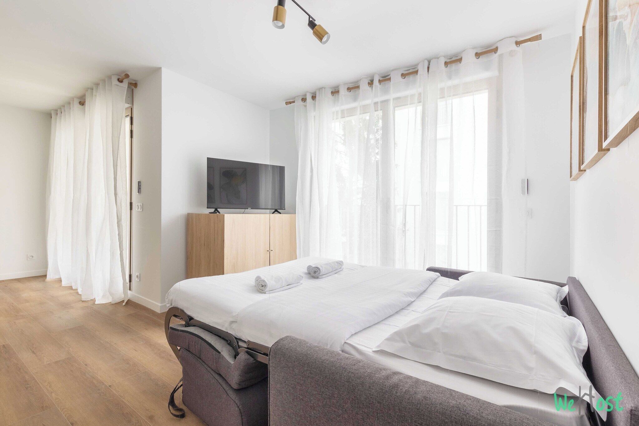 Quarto de hotel moderno com uma cama grande, televisão de tela plana e um armário de madeira.
