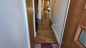 Un couloir étroit, doté d’un plancher en bois et d’un tapis à l’entrée.