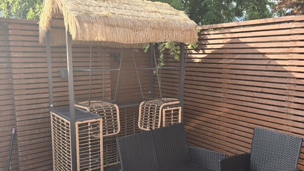 Un espace extérieur aménagé avec des meubles en osier et un toit de chaume.