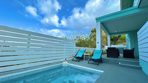 A modern outdoor pool area with a clear blue sky, a pool with blue tiles, and two lounge chairs. - Hillside Escape- Private Pool & Breathtaking Sunset Over the Town (Bequia)