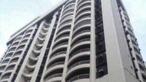 A high-rise building with multiple balconies and a curved facade. - Apê da Mi (Guaruja)