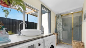 Ein modernes Badezimmer mit einer Waschmaschine von Bosch, einem Waschbecken und einer Duschkabine.