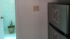 Eine Küche mit Kühlschrank, einer Wandsteckdose und einem Blumentopf.