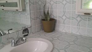Ein Badezimmer mit Waschbecken, Spiegel und einer Zimmerpflanze.