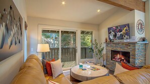 A living room with a stone fireplace, a television, and a large window.