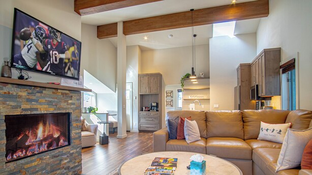 A living room with a fireplace, a television, a round coffee table, and a leather sofa.