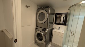 A compact bathroom with a washing machine, a glass shower enclosure, and a small vanity. - Cozy & Private Suite w/ Private Entrance & Parking (Richmond Hill)