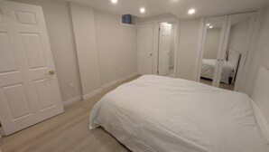 A bedroom with a large bed, a wardrobe, and a mirror.