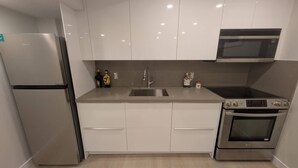 A modern kitchen with white cabinets, stainless steel appliances, a sink, and a microwave.