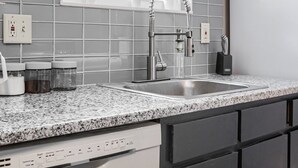 Una cocina con encimera de granito, pileta de acero inoxidable y lavavajillas.