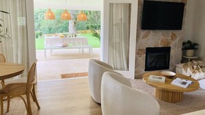 Una sala de estar con chimenea de piedra, un televisor de pantalla plana montado encima y un comedor con mesa y sillas de madera.