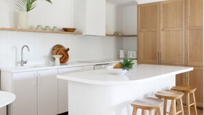 Una cocina moderna con armarios blancos, una isla central con taburetes y una encimera de madera.