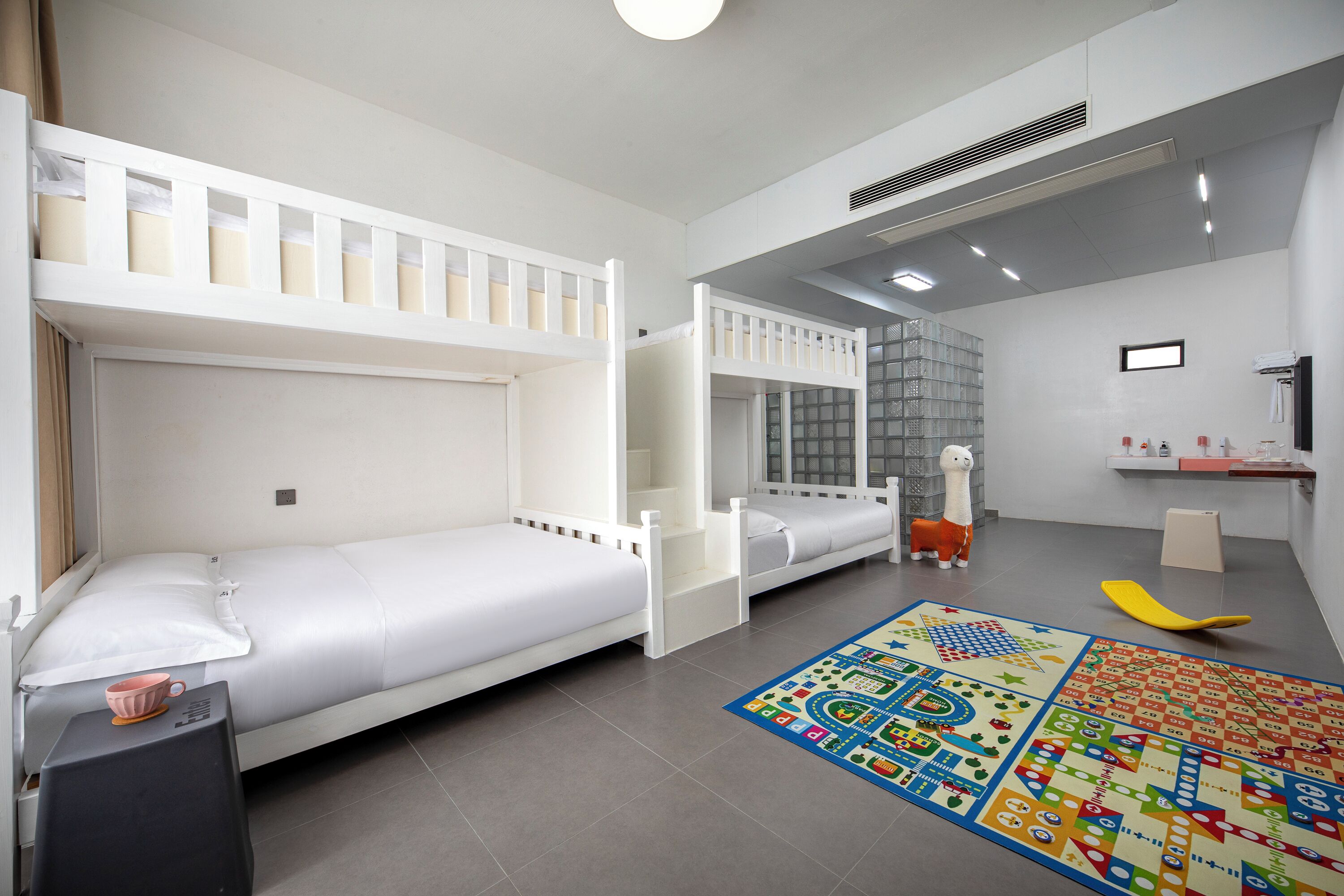 A child's bedroom with bunk beds, a play mat, and a toy horse.