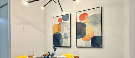 A dining area with a black table, yellow chairs, and abstract wall art.