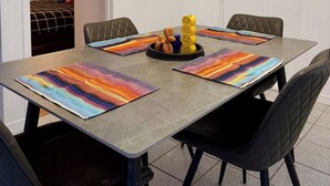 A dining area with a long table, black chairs, and a modern chandelier. - Charming, well-furnished apartment (Québec)