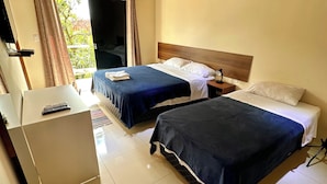 A hotel room with two beds, a desk, and a TV. - Hotel Junior (Caazapá)