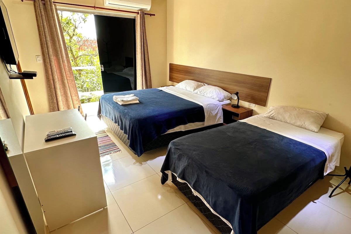 A hotel room with two beds, a desk, and a TV.