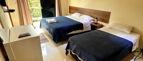 Een hotelkamer met twee bedden, een bureau en een televisie.