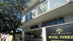 A hotel named 'Hotel Junior' with a modern facade, large windows, and a visible air conditioning unit. - Hotel Junior (Caazapá)