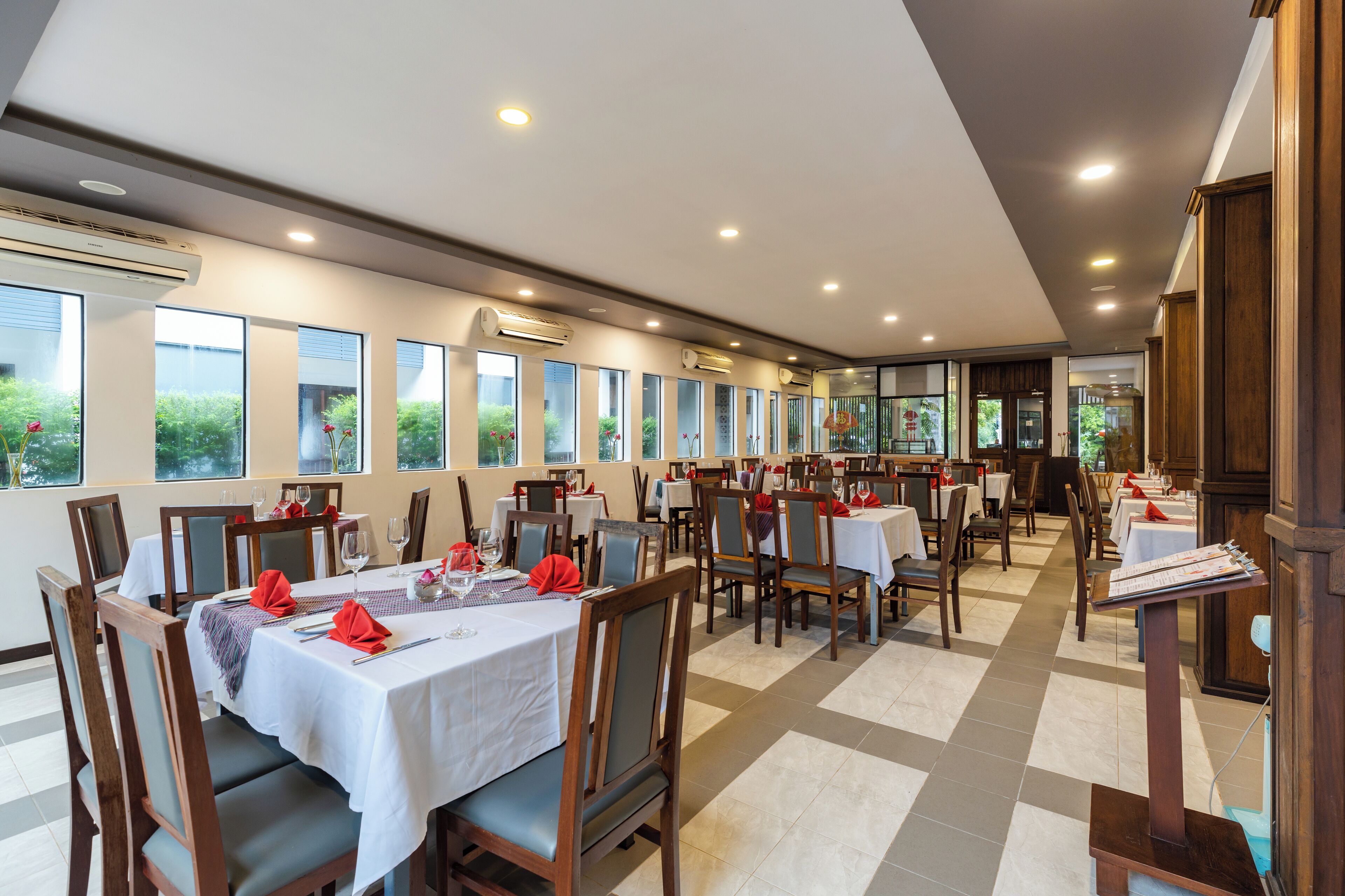 Un restaurant doté de nombreuses tables et chaises, de climatiseurs et de grandes fenêtres.