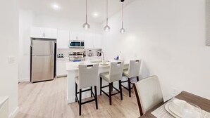 Een moderne keuken met witte kastjes, een roestvrijstalen koelkast en een centraal eiland met barstoelen.
