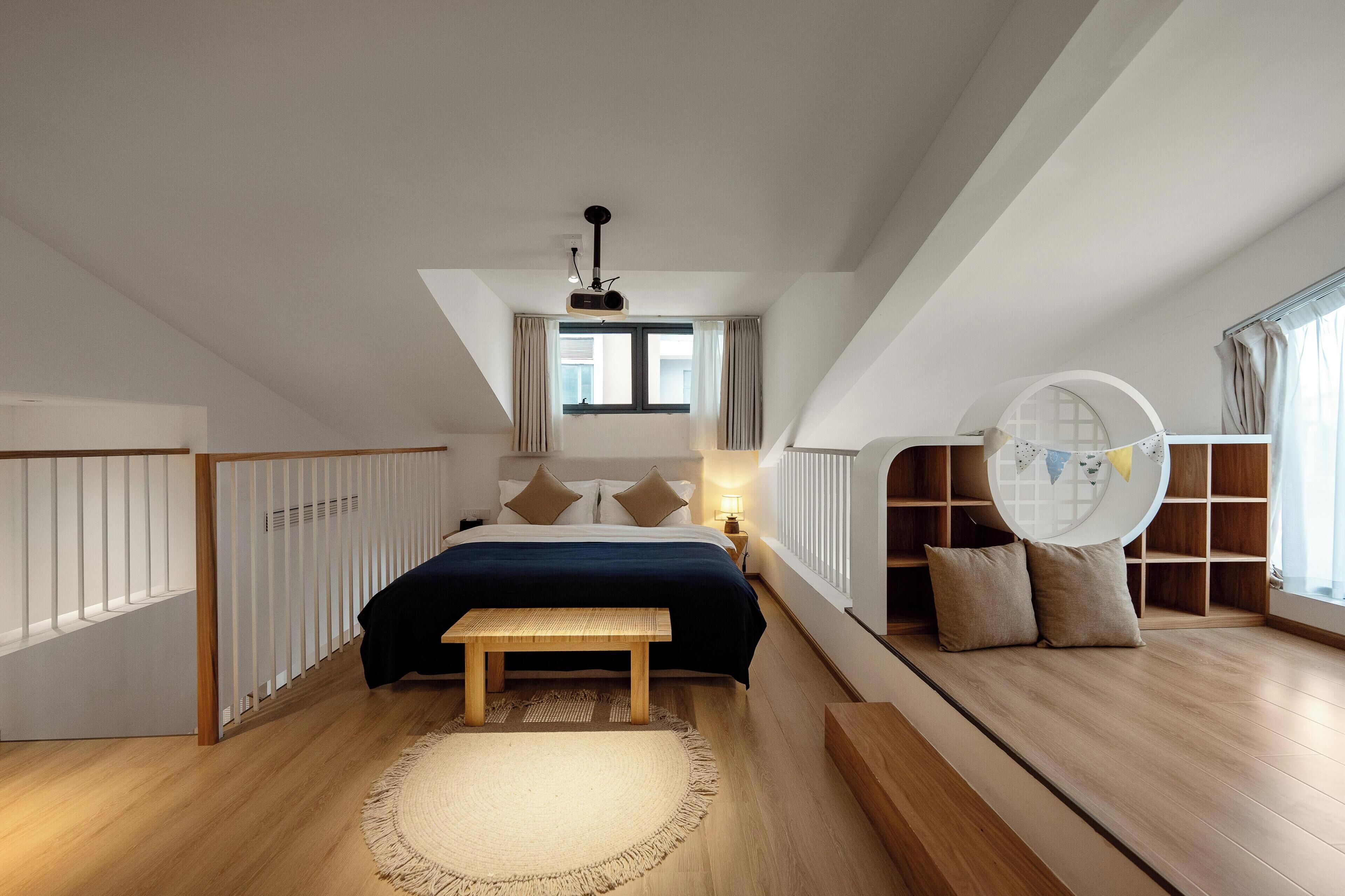 A bedroom with a bed, a bench, a circular shelf, and a window.