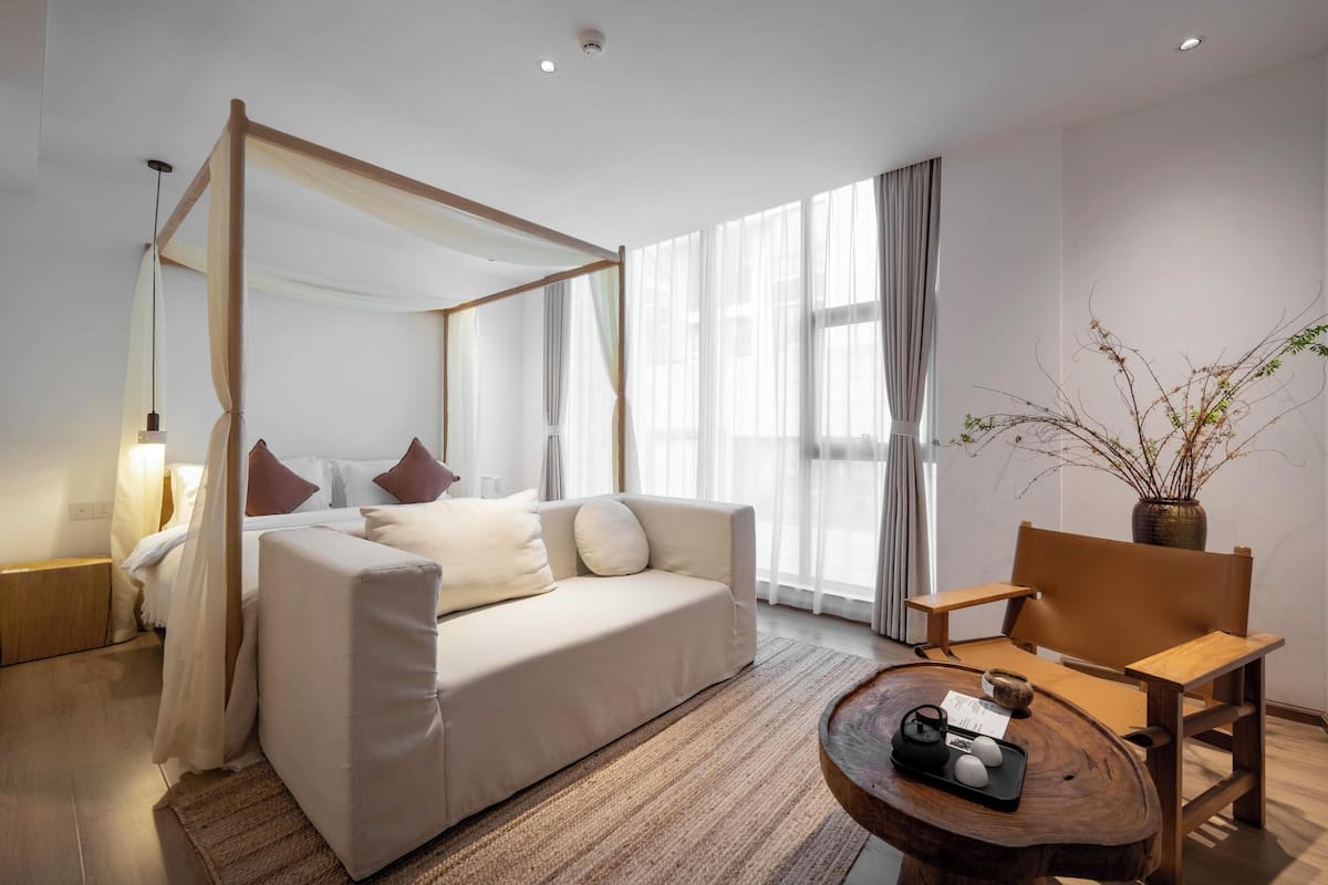 Een moderne hotelkamer met een bed, een bank, een houten salontafel en een stoel.