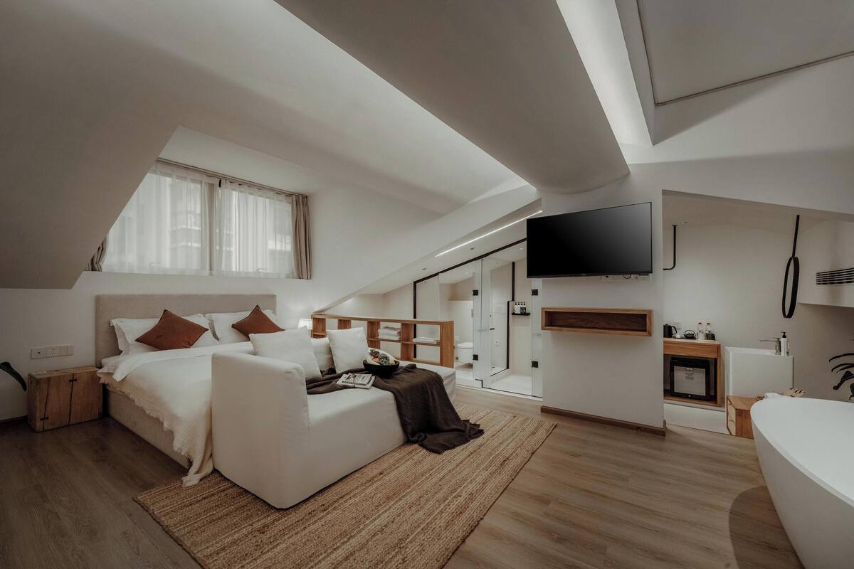 Een moderne slaapkamer met een bed, nachtkastjes, een televisie en een douche.