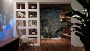 A modern living room with wooden flooring, a projection screen, a wooden chair, and a stone wall. - Leli Villa Designer - Vacation Homestay (Qiandongnan)