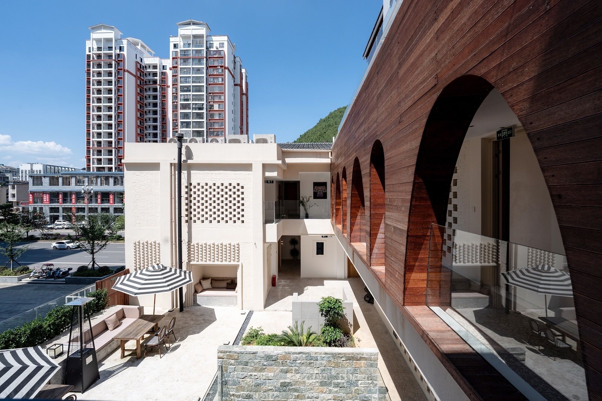 A modern building with a courtyard, featuring a seating area with a table and chairs, and a covered outdoor space.