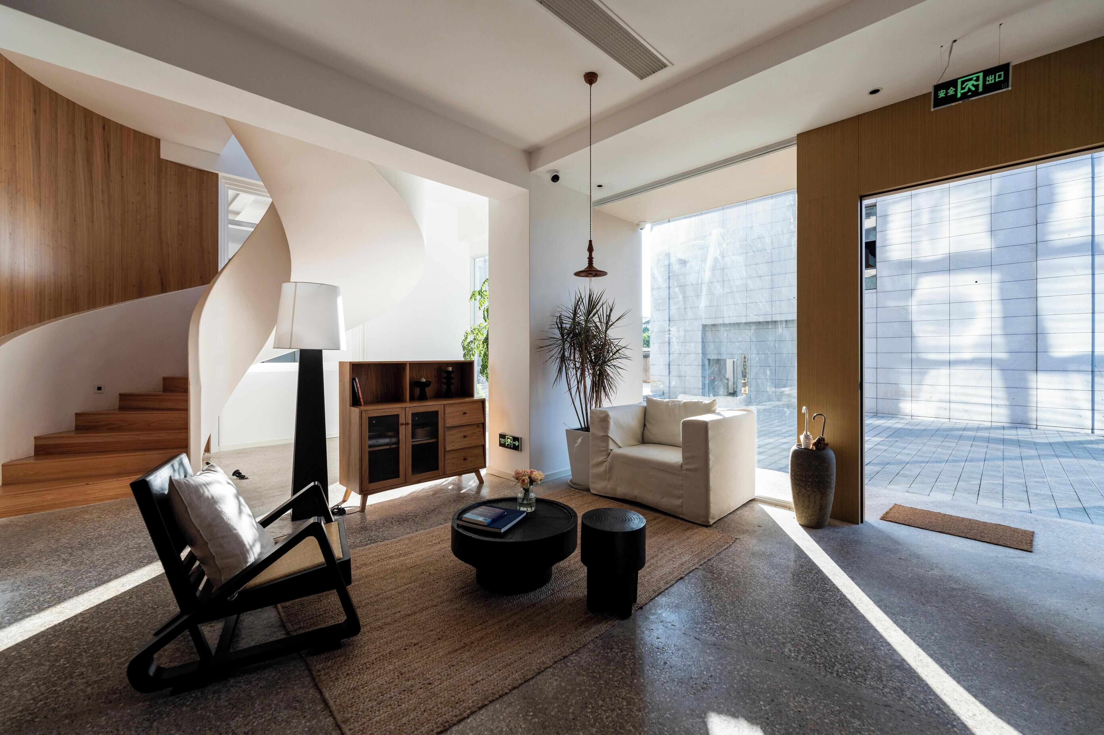 Un interior moderno con una escalera en espiral, un sofá, una mesa de centro y una planta en maceta.
