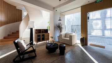 Un interior moderno con una escalera en espiral, un sofá, una mesa de centro y una planta en maceta.
