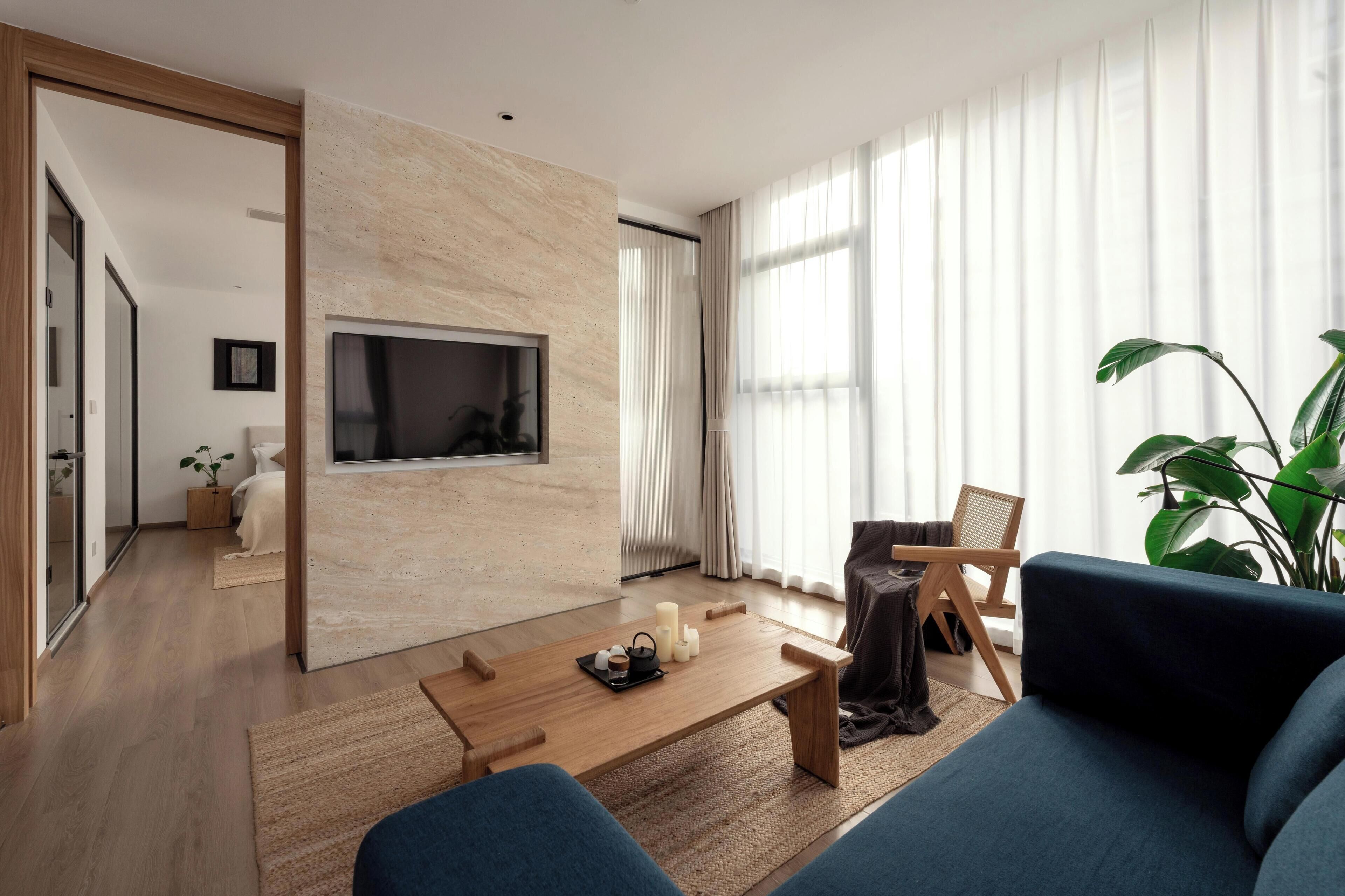 A modern living room with a wooden coffee table, a blue sofa, and a large plant.