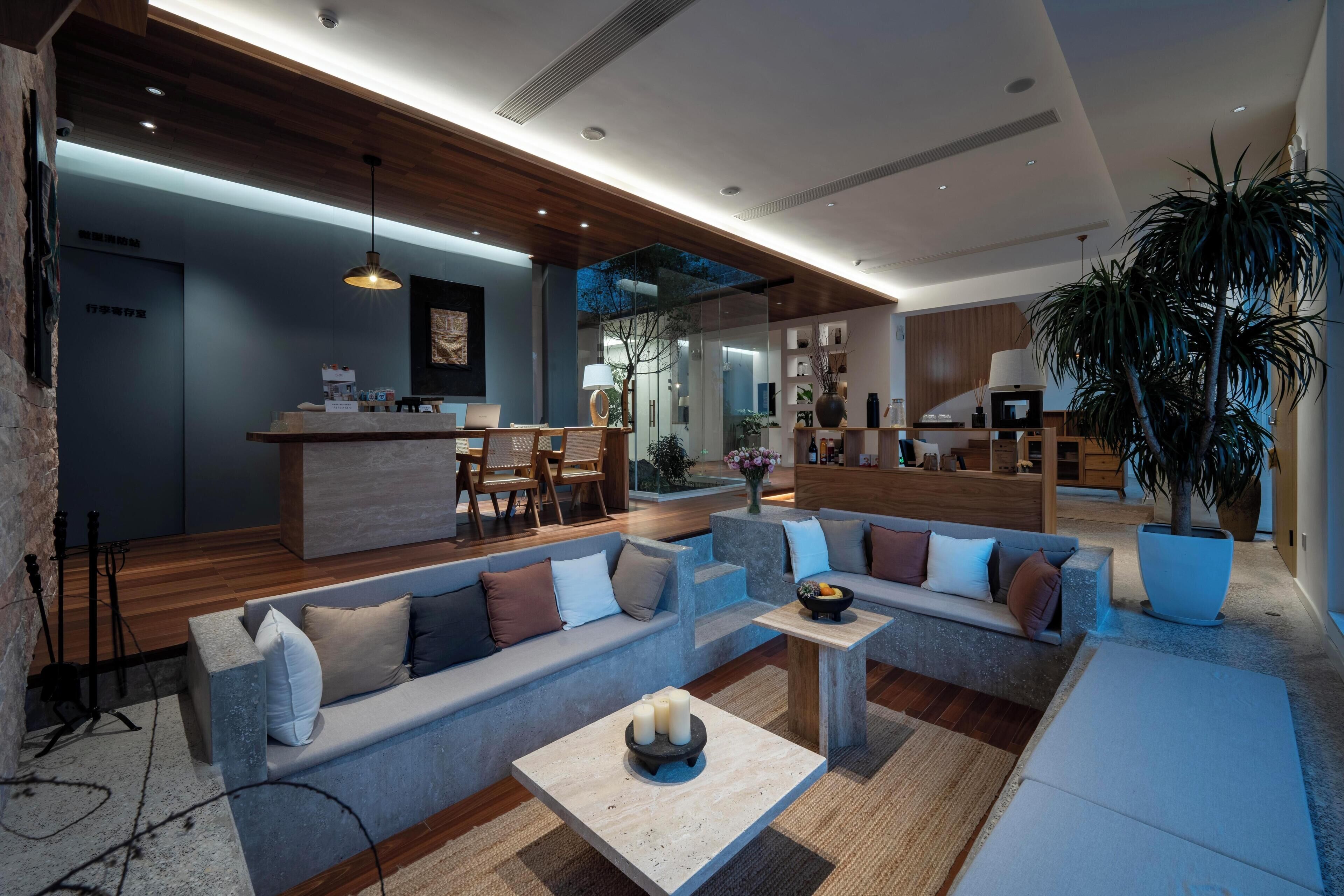 Una sala de estar moderna con un sofá modular, una mesa de centro y una planta grande en maceta.