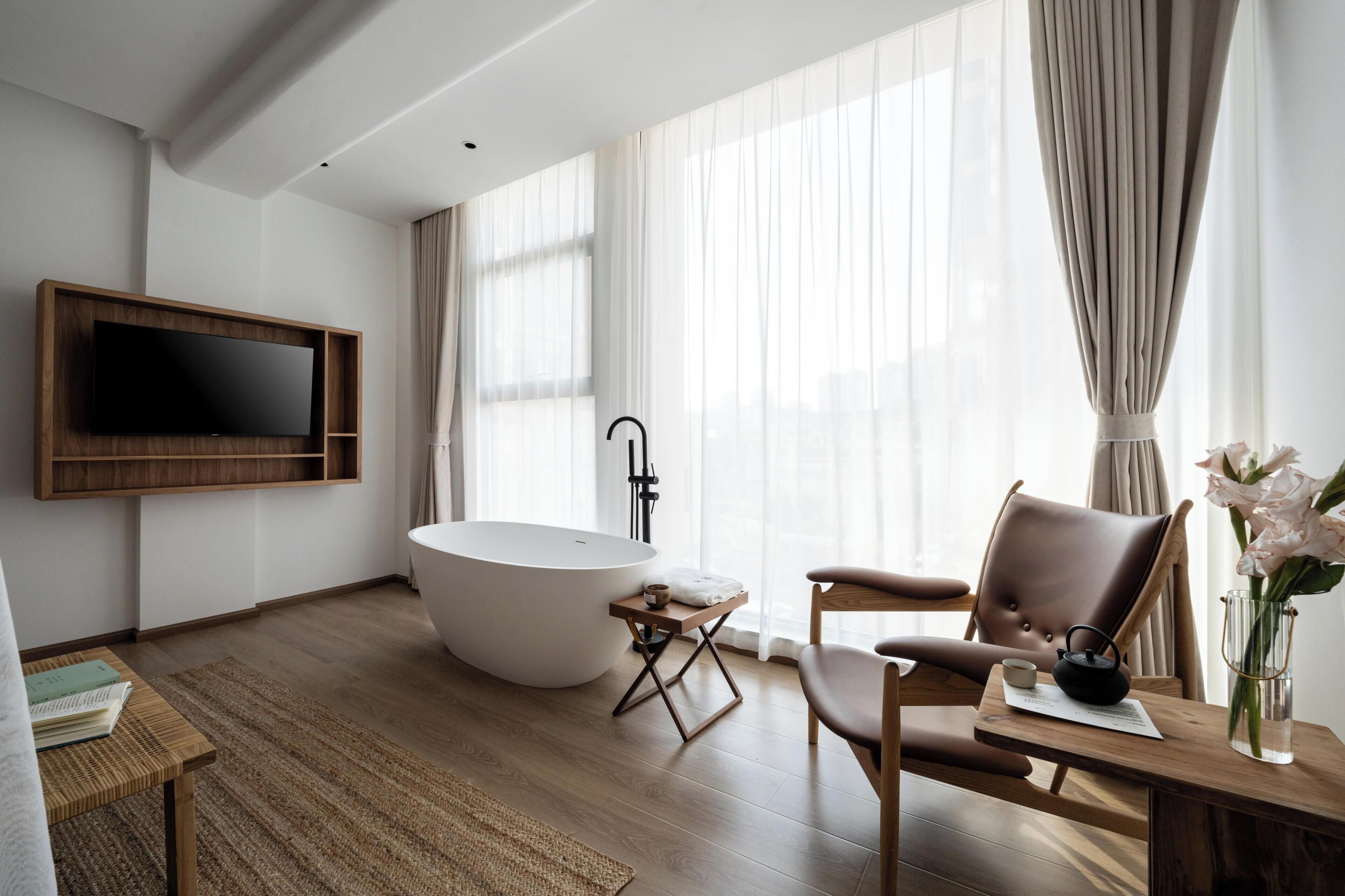 Une salle de bain moderne avec une baignoire sur pieds, un meuble-lavabo en bois et un téléviseur à écran plat fixé au mur.