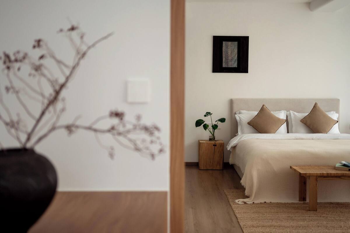 Een slaapkamer met een bed, nachtkastje en een klein houten kastje.
