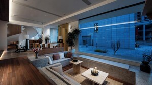 A modern interior with a large window, a sofa, a small table, and a staircase. - Leli Villa Designer - Vacation Homestay (Qiandongnan)