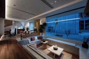 Un interior moderno con un ventanal amplio, un sofá, una mesita y una escalera.